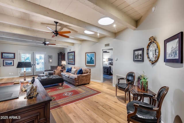 living room with ceiling fan, light wood-type flooring, beam ceiling, and baseboards