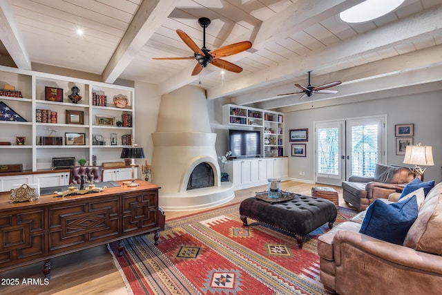living area featuring wood finished floors, beam ceiling, a ceiling fan, wood ceiling, and a large fireplace