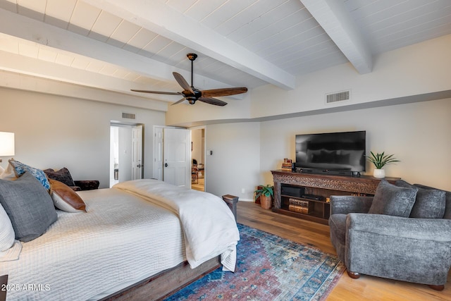 bedroom with wood finished floors, beam ceiling, and ceiling fan