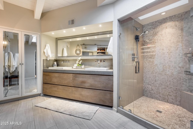 bathroom with a stall shower, double vanity, beam ceiling, and recessed lighting
