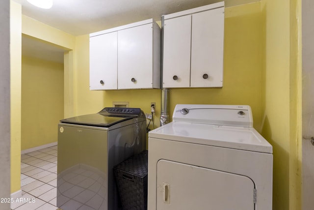 laundry area featuring light tile patterned floors, cabinets, and washing machine and clothes dryer