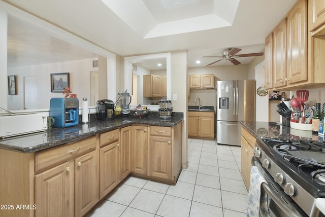 kitchen with light brown cabinetry, sink, dark stone counters, ceiling fan, and stainless steel appliances