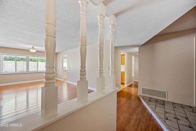 corridor featuring a textured ceiling, wood finished floors, and baseboards