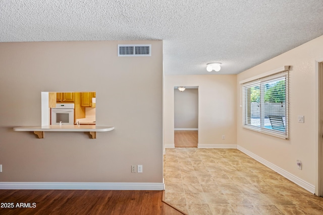 unfurnished room featuring a textured ceiling and baseboards