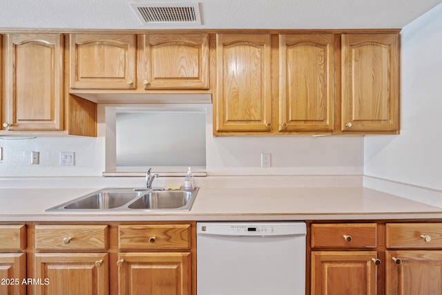 kitchen featuring white dishwasher, a sink, and light countertops