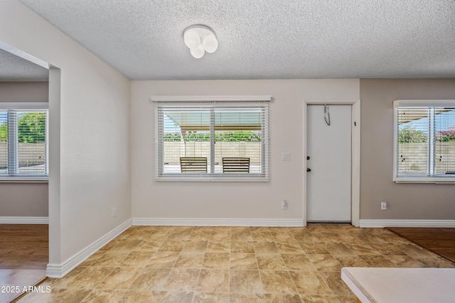 foyer featuring a textured ceiling and baseboards