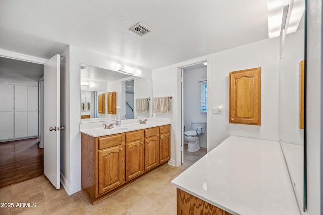 bathroom featuring toilet, tile patterned floors, and double vanity