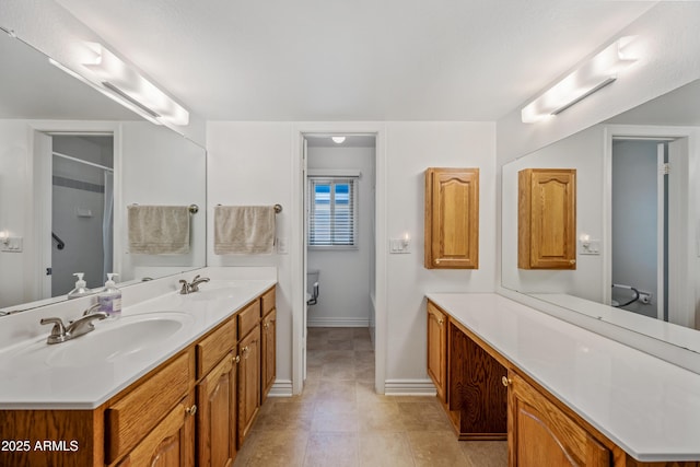 full bathroom featuring baseboards, double vanity, a shower, tile patterned flooring, and toilet