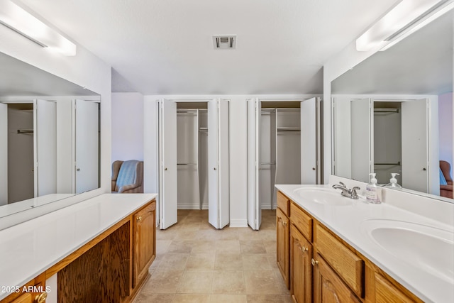 full bathroom featuring double vanity, a walk in closet, and baseboards