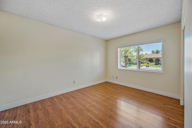 spare room with wood finished floors, baseboards, and a textured ceiling