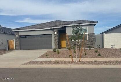 25235 N 183rd Dr, Wittmann, AZ 85361 - view of front facade featuring concrete driveway, an attached garage, fence, and stone siding