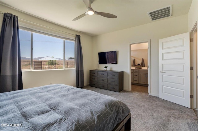 bedroom featuring ceiling fan, ensuite bathroom, and light carpet