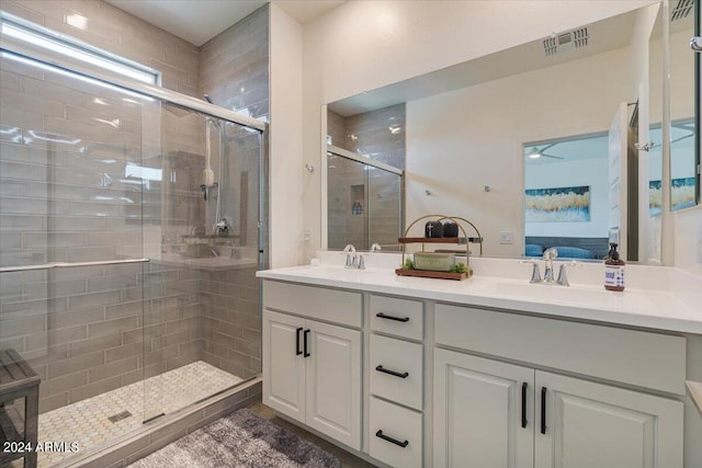 bathroom with a shower with shower door and double sink vanity