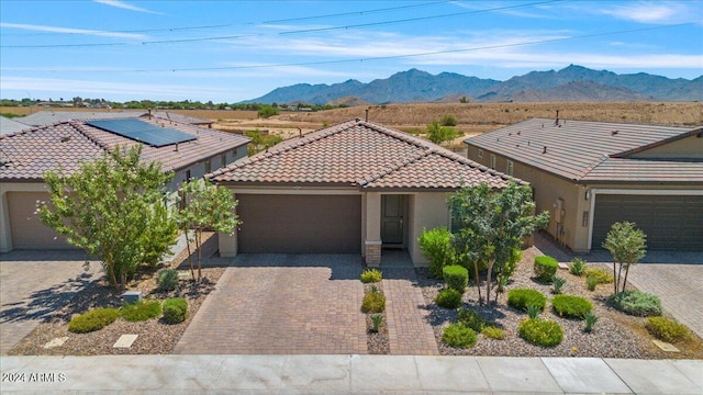 view of front facade featuring solar panels, a mountain view, and a garage