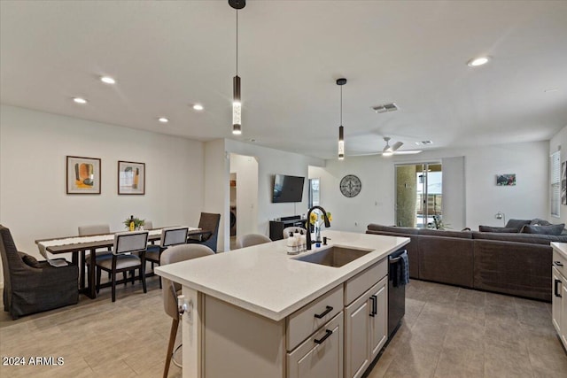 kitchen with hanging light fixtures, an island with sink, ceiling fan, sink, and stainless steel dishwasher