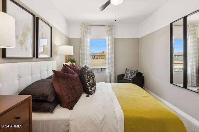 carpeted bedroom featuring multiple windows, baseboards, and ceiling fan