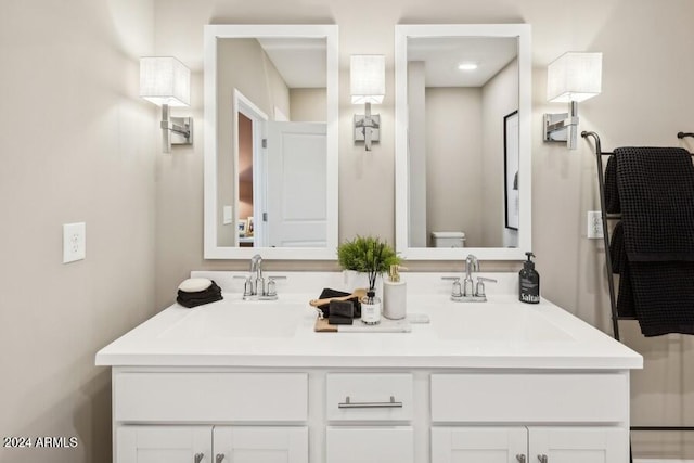 full bath with a sink, toilet, and double vanity