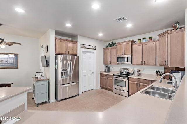 kitchen with stainless steel appliances, sink, light tile patterned floors, and ceiling fan