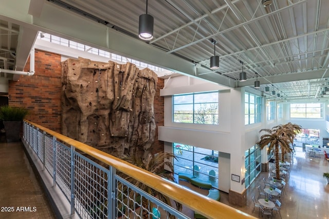 hall with brick wall, plenty of natural light, and a towering ceiling