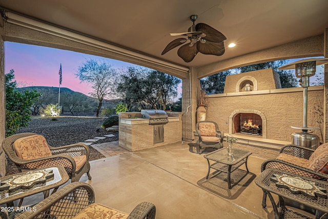 view of patio / terrace featuring area for grilling, ceiling fan, and an outdoor living space with a fireplace