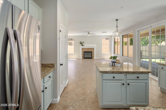 7758 E Nestling Way, Scottsdale, AZ 85255 - kitchen featuring freestanding refrigerator, light tile patterned floors, ceiling fan, a center island, and decorative light fixtures