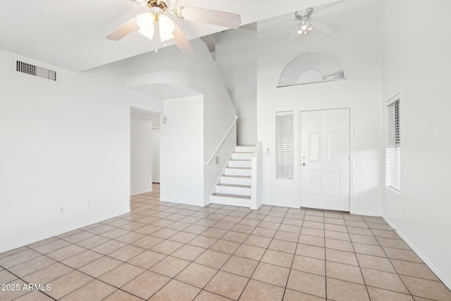 tiled entrance foyer with ceiling fan and a towering ceiling