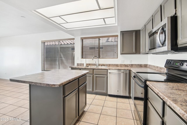 kitchen with stainless steel appliances, sink, gray cabinets, a kitchen island, and light tile patterned flooring