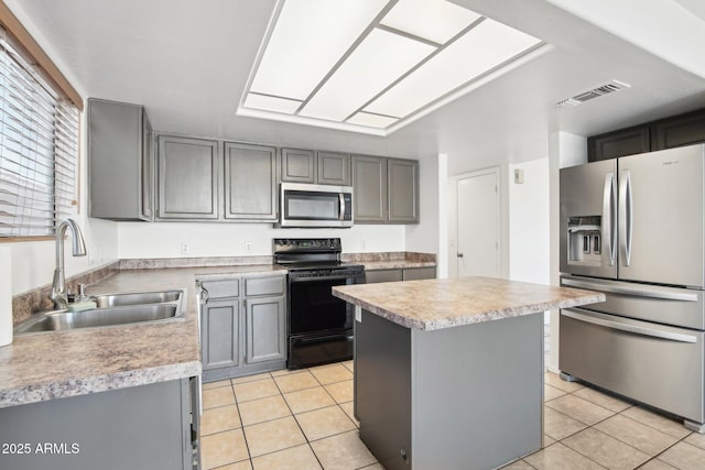 kitchen with light tile patterned flooring, sink, a kitchen island, and stainless steel appliances