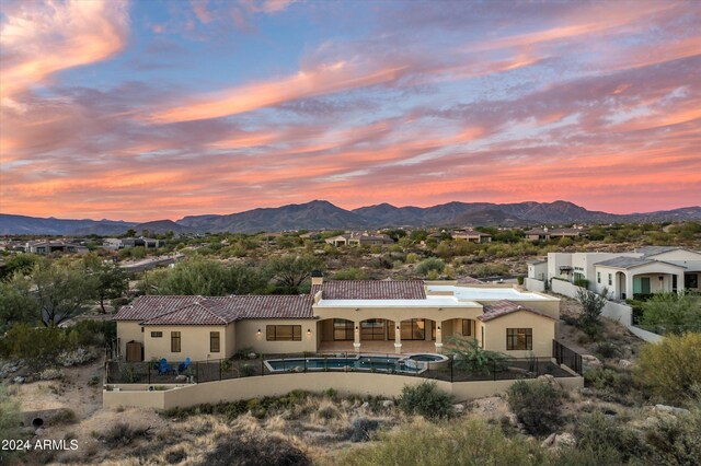 back house at dusk featuring an in ground hot tub and a mountain view