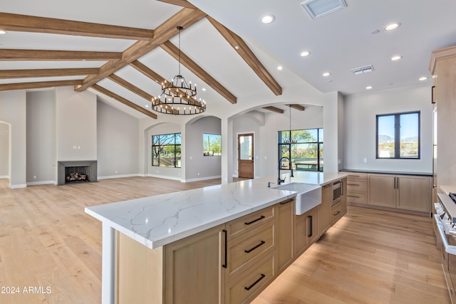 kitchen featuring a large island, light stone countertops, sink, and light brown cabinets