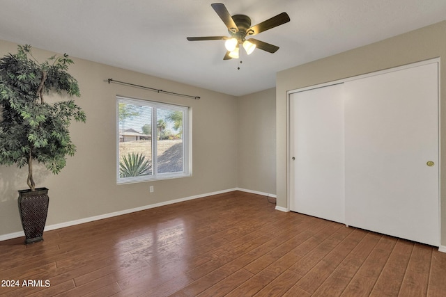 unfurnished bedroom featuring a ceiling fan, a closet, baseboards, and wood finished floors