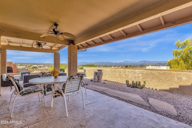 view of patio / terrace with a ceiling fan, outdoor dining space, and a mountain view