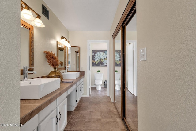 full bath featuring a textured wall, visible vents, a sink, and toilet