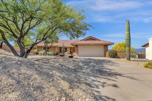 single story home with an attached garage, fence, a tile roof, concrete driveway, and stucco siding