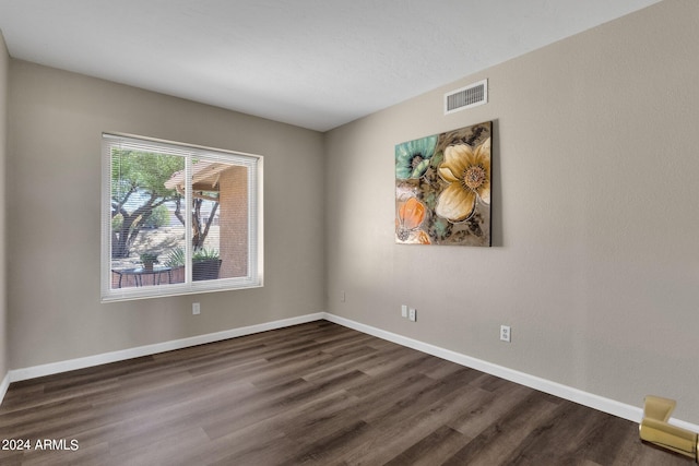 spare room featuring baseboards, visible vents, and dark wood-type flooring