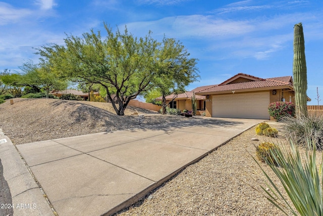 ranch-style home with a garage, concrete driveway, a tiled roof, fence, and stucco siding