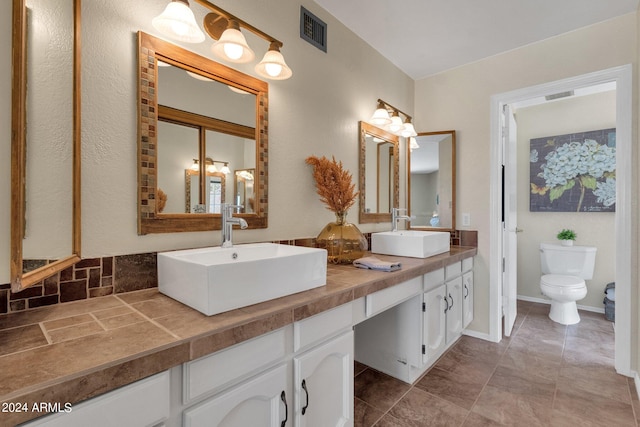 bathroom featuring toilet, visible vents, and a sink