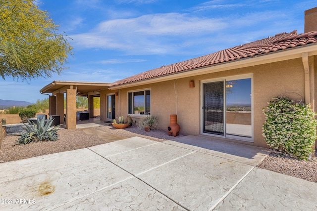 rear view of property with a patio area, a tiled roof, and stucco siding