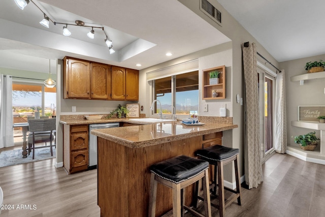 kitchen with visible vents, dishwasher, brown cabinets, a peninsula, and a sink