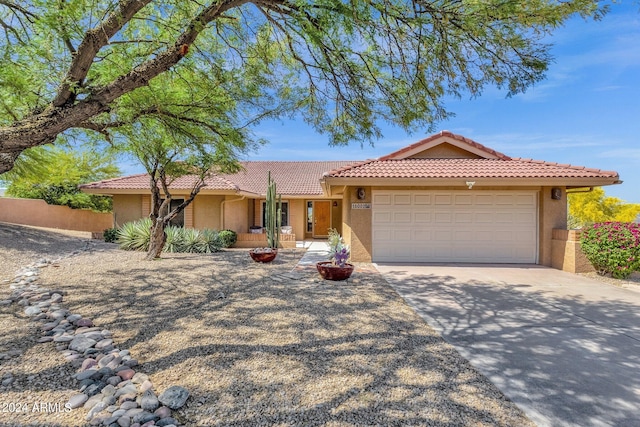 ranch-style house featuring a garage, concrete driveway, a tile roof, and stucco siding