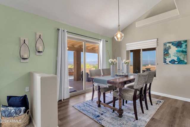 dining space with vaulted ceiling, baseboards, and wood finished floors