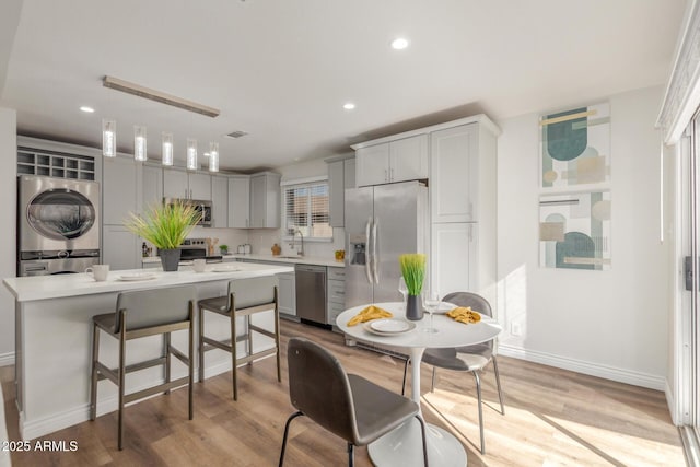 kitchen with stacked washer and dryer, appliances with stainless steel finishes, pendant lighting, and a kitchen island