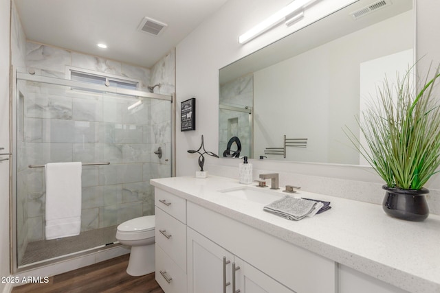 bathroom with toilet, vanity, a shower with door, and hardwood / wood-style floors