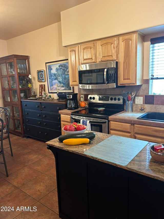 kitchen with decorative backsplash, dark tile patterned floors, appliances with stainless steel finishes, and sink