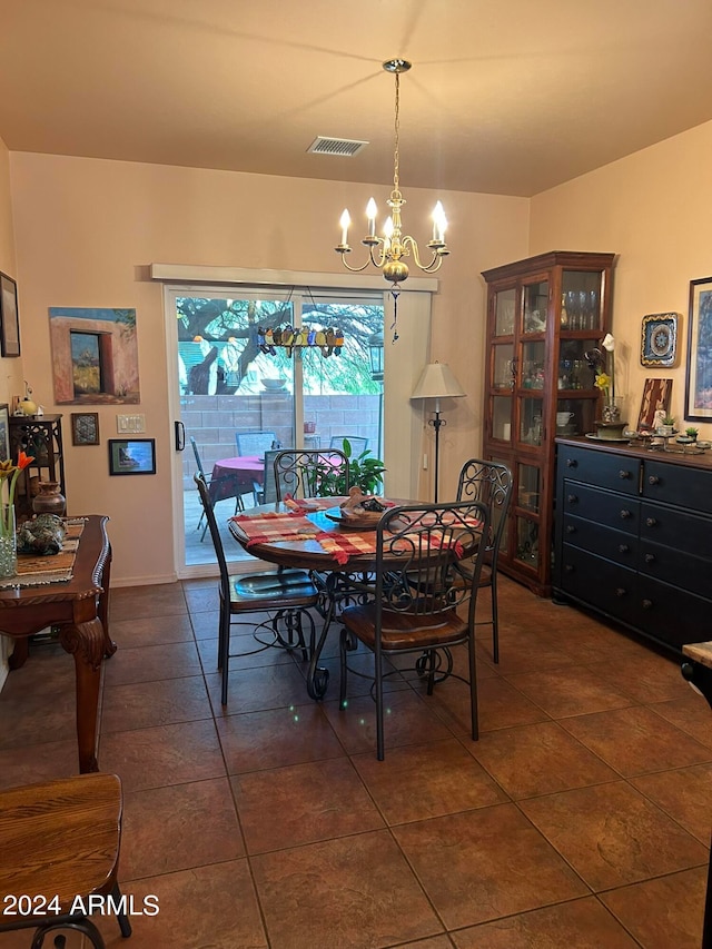 dining space featuring dark tile patterned flooring and an inviting chandelier