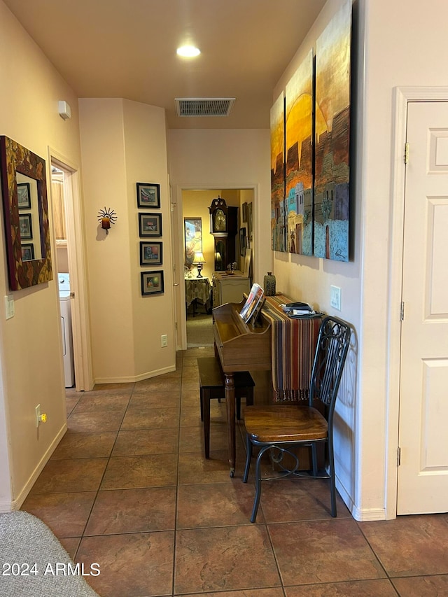 hallway featuring dark tile patterned flooring and washer / dryer