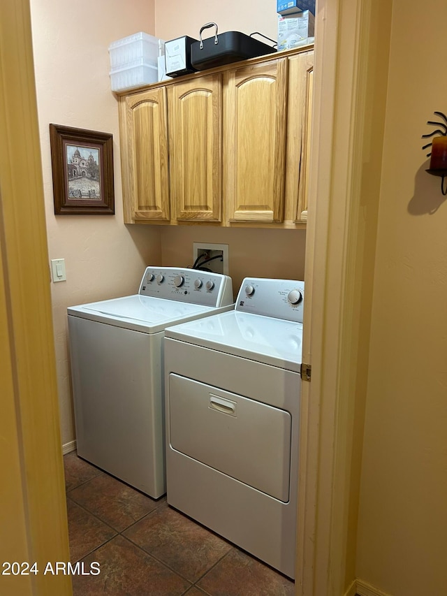 clothes washing area with separate washer and dryer, cabinets, and dark tile patterned floors