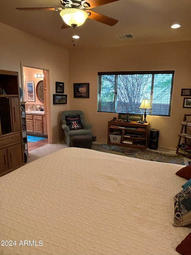 bedroom with ceiling fan, connected bathroom, and light carpet