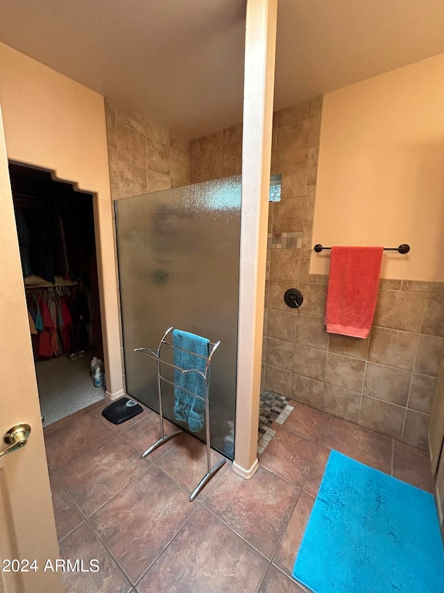 bathroom with a tile shower and tile walls