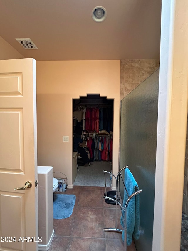 bathroom with tile patterned flooring, a shower with door, and toilet